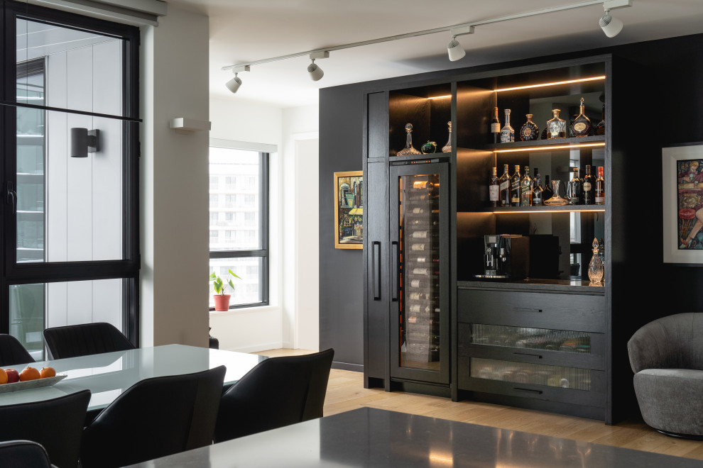 Immagine di un grande angolo bar senza lavandino moderno con ante in legno bruno, top in granito, paraspruzzi nero, paraspruzzi con lastra di vetro e top nero