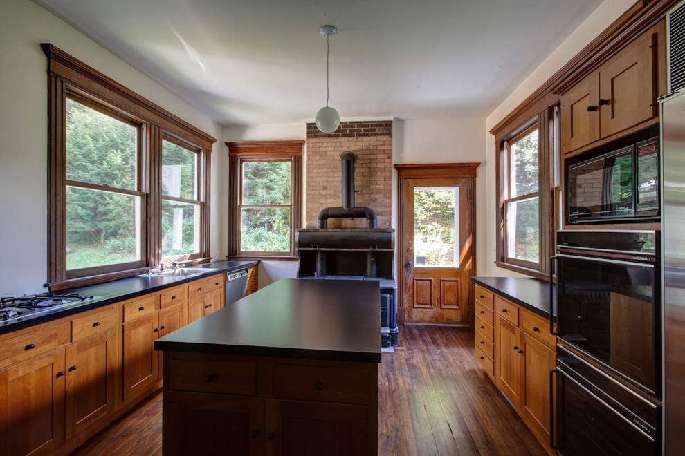 Inspiration for a mid-sized traditional kitchen in New York with a drop-in sink, shaker cabinets, medium wood cabinets, laminate benchtops, stainless steel appliances, dark hardwood floors and with island.