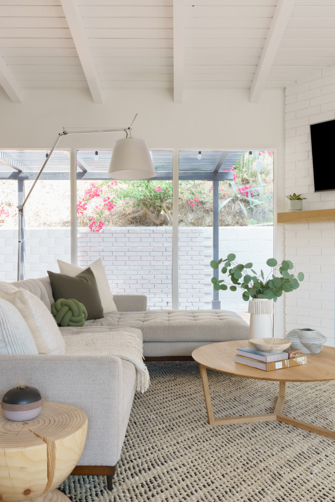 Inspiration for a small mid-century modern open concept medium tone wood floor, brown floor and shiplap ceiling living room remodel in Los Angeles with white walls, a corner fireplace, a brick fireplace and a corner tv