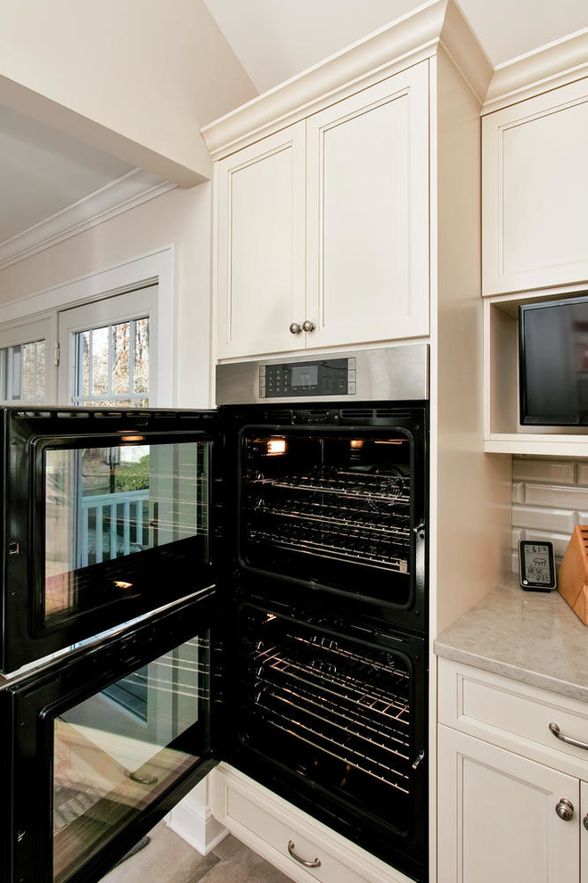 Mid-sized transitional u-shaped porcelain tile eat-in kitchen photo in New York with an undermount sink, recessed-panel cabinets, white cabinets, wood countertops, gray backsplash, subway tile backsplash, stainless steel appliances and an island