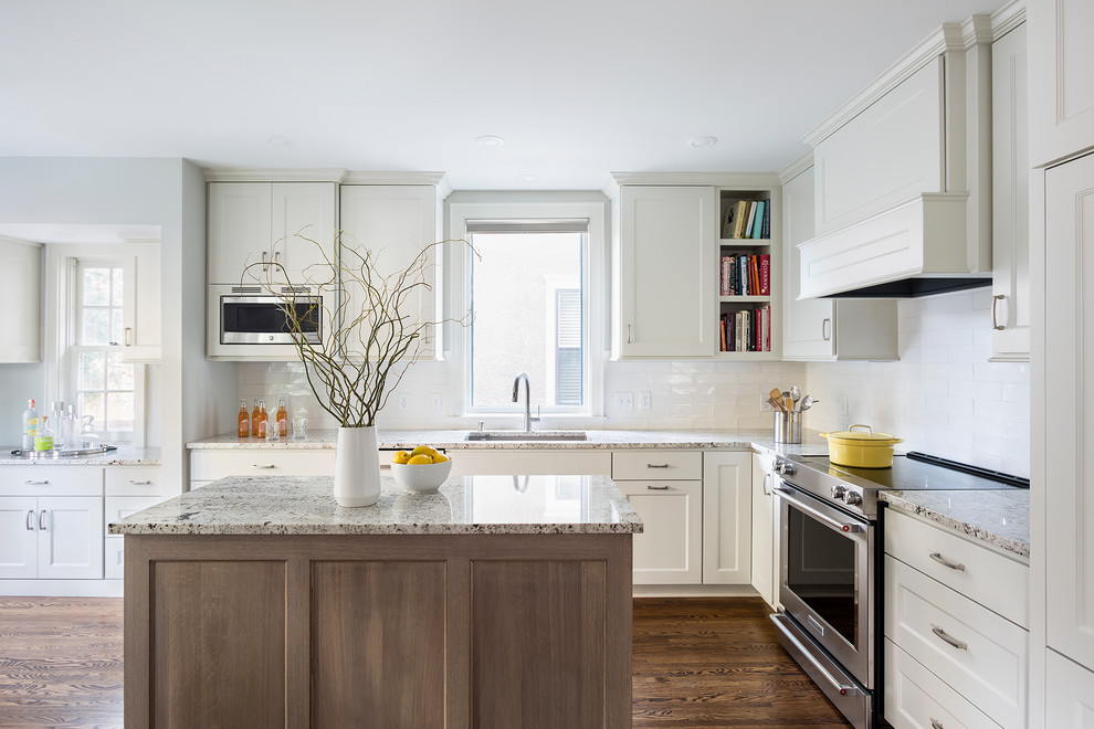 Design ideas for a mid-sized transitional l-shaped separate kitchen in Minneapolis with an undermount sink, flat-panel cabinets, grey cabinets, granite benchtops, white splashback, ceramic splashback, panelled appliances, medium hardwood floors, with island and brown floor.