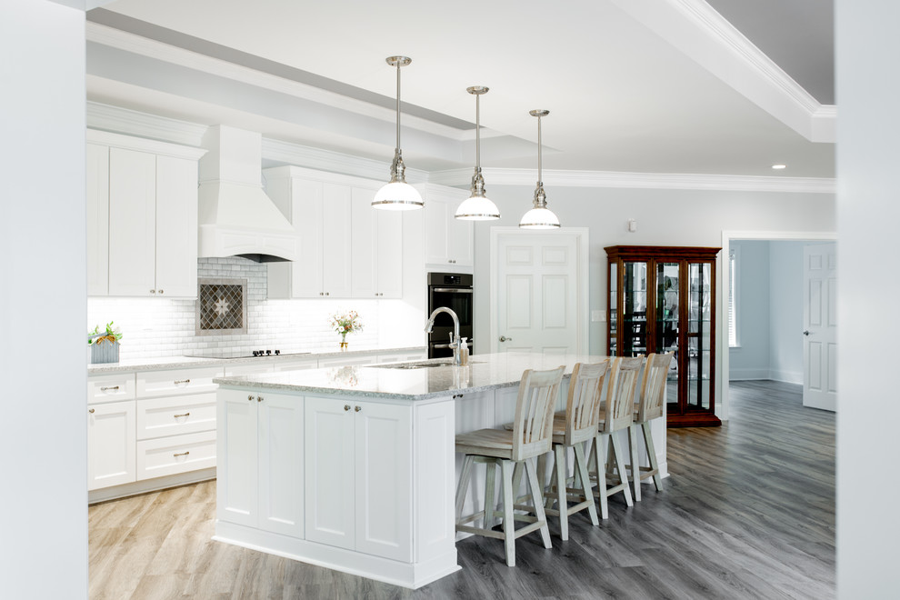 Design ideas for an expansive transitional l-shaped eat-in kitchen in Charlotte with a triple-bowl sink, shaker cabinets, white cabinets, quartz benchtops, white splashback, marble splashback, stainless steel appliances, light hardwood floors, with island, grey floor and multi-coloured benchtop.