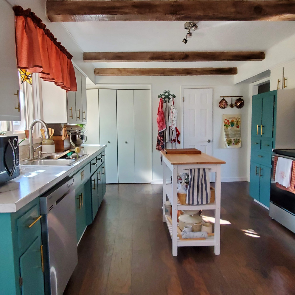 This is an example of a mid-sized eclectic galley open plan kitchen in Other with a drop-in sink, flat-panel cabinets, turquoise cabinets, laminate benchtops, beige splashback, stone tile splashback, stainless steel appliances, vinyl floors, with island, brown floor, white benchtop and exposed beam.