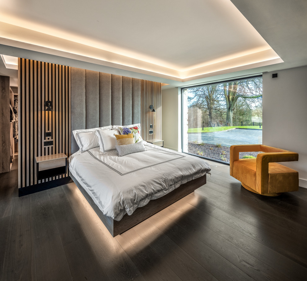 Immagine di una camera da letto minimal con pareti grigie, parquet scuro, pavimento marrone e soffitto ribassato