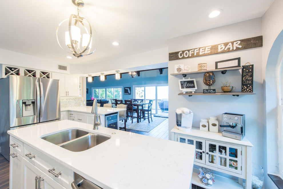 Example of a large transitional u-shaped porcelain tile and brown floor eat-in kitchen design with an undermount sink, shaker cabinets, white cabinets, quartz countertops, white backsplash, marble backsplash, stainless steel appliances and two islands