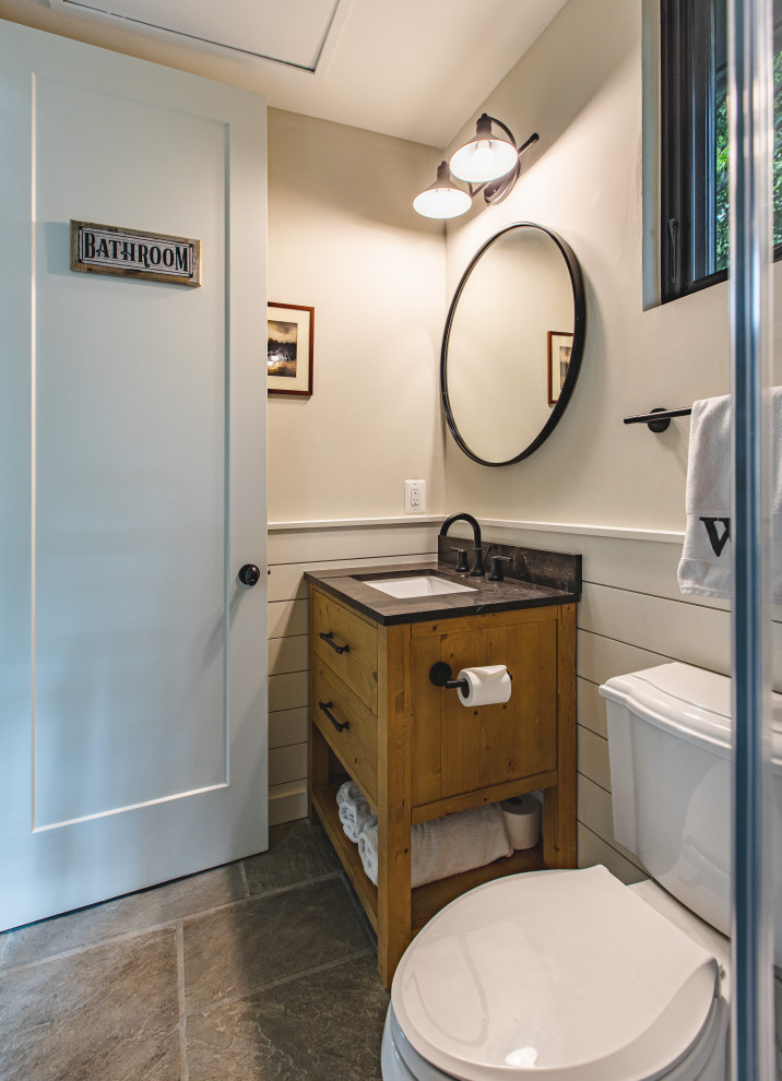 Photo of a small modern master bathroom in DC Metro with furniture-like cabinets, brown cabinets, an alcove shower, a two-piece toilet, beige tile, porcelain tile, beige walls, slate floors, an undermount sink, quartzite benchtops, multi-coloured floor, a hinged shower door, black benchtops, an enclosed toilet, a single vanity, a freestanding vanity, vaulted and planked wall panelling.