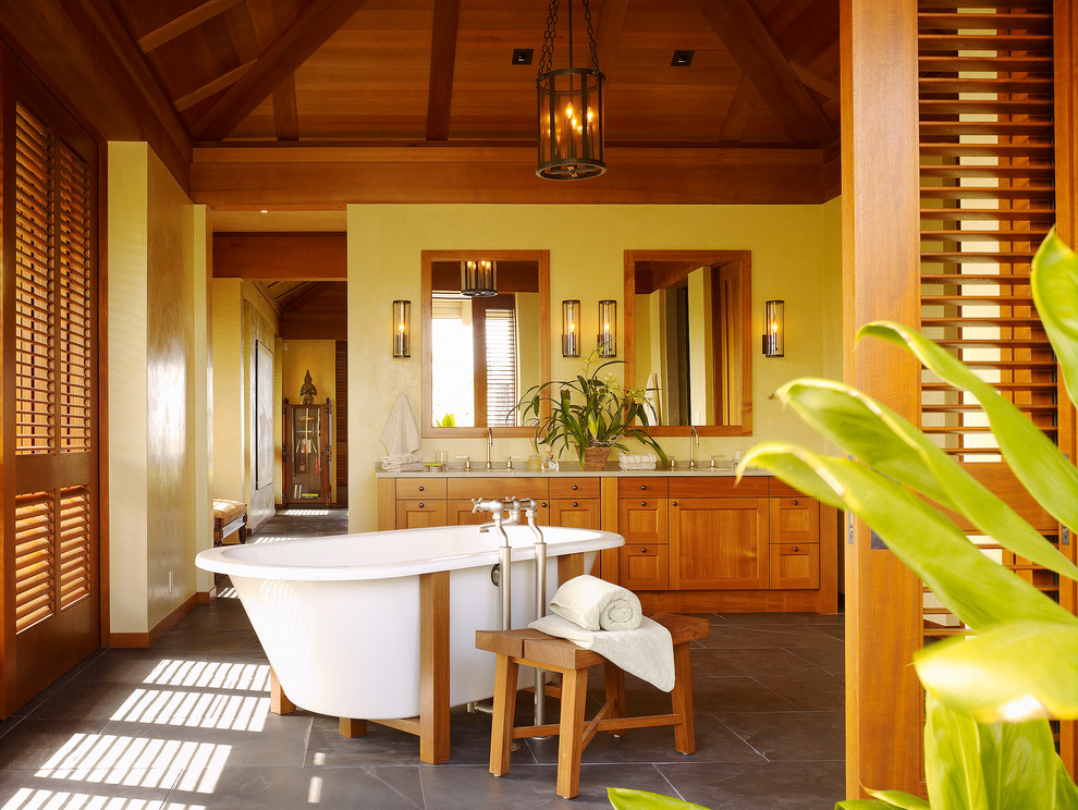 This is an example of a tropical bathroom in Hawaii with a freestanding tub and slate floors.