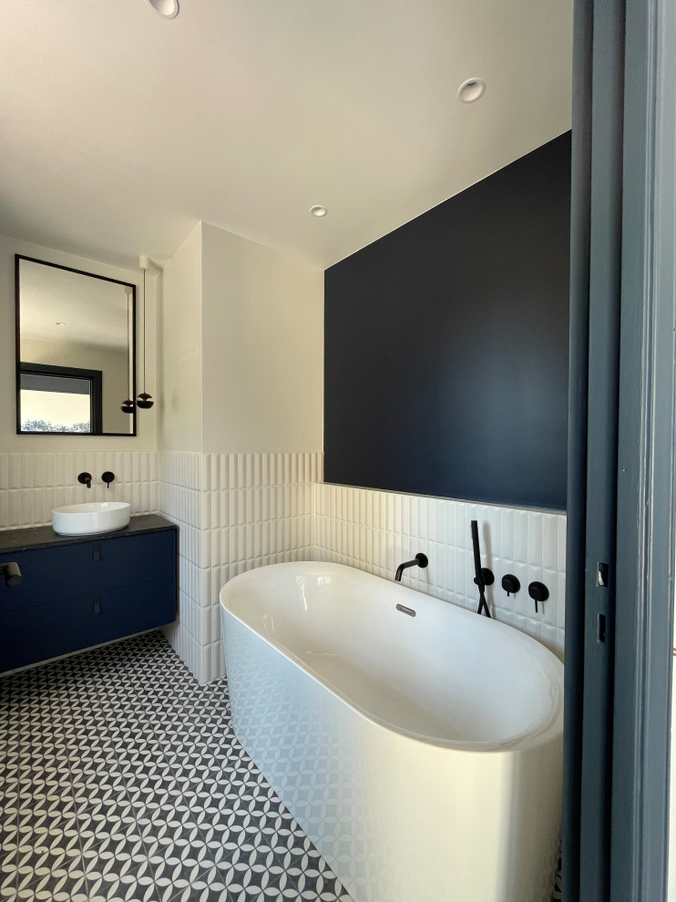 Inspiration for a large world-inspired ensuite bathroom in Nice with blue cabinets, an alcove bath, a wall mounted toilet, white tiles, matchstick tiles, white walls, cement flooring, a console sink, marble worktops, an open shower, black worktops, a single sink and a floating vanity unit.