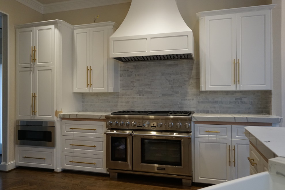 Inspiration for a large transitional open plan kitchen in Dallas with white cabinets, raised-panel cabinets, marble benchtops, multi-coloured splashback, stone tile splashback, stainless steel appliances and medium hardwood floors.