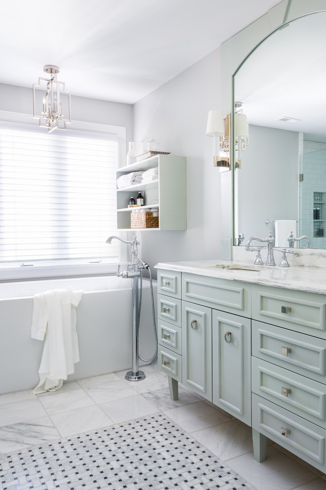Inspiration for a mid-sized traditional master bathroom in St Louis with blue cabinets, a freestanding tub, white tile, marble, grey walls, marble floors, an undermount sink, marble benchtops, white floor, white benchtops and recessed-panel cabinets.