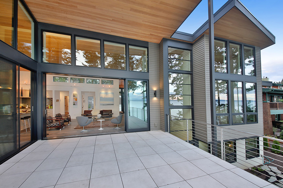 Large modern balcony in Seattle with a roof extension and cable railing.