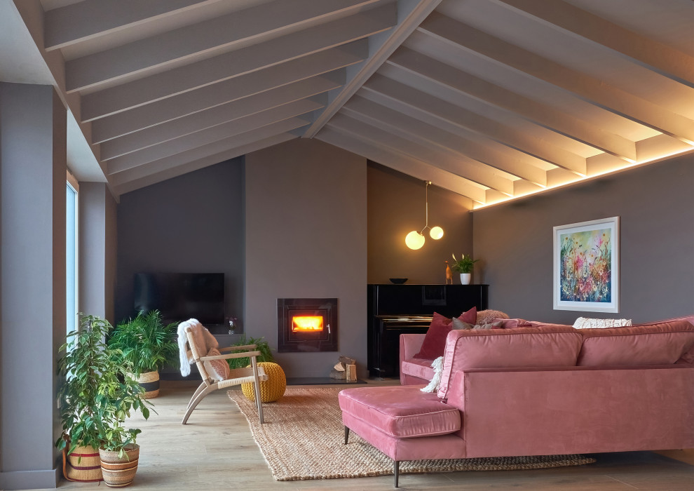 Mittelgroßes, Abgetrenntes Modernes Wohnzimmer mit brauner Wandfarbe, Laminat, Kaminofen, braunem Boden und freigelegten Dachbalken in Dublin