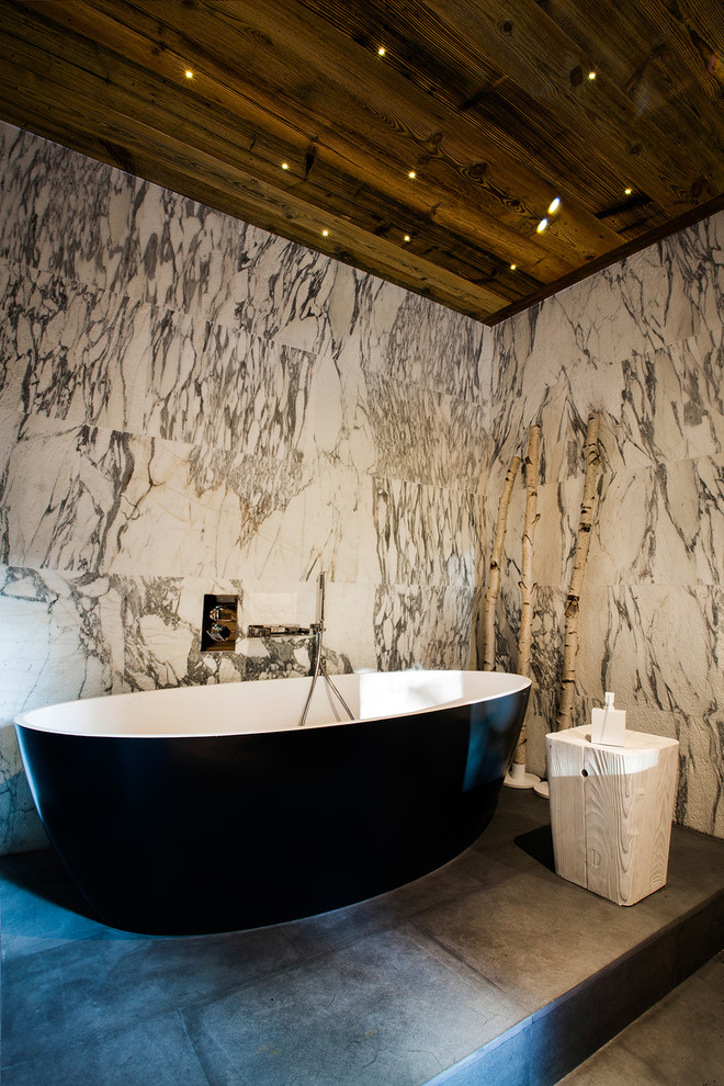 Photo of a mid-sized eclectic master bathroom in Lyon with a freestanding tub and gray tile.
