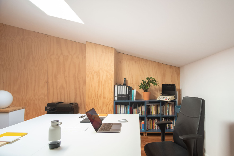 Imagen de despacho actual de tamaño medio con paredes blancas, suelo de madera en tonos medios, escritorio independiente, suelo marrón y madera