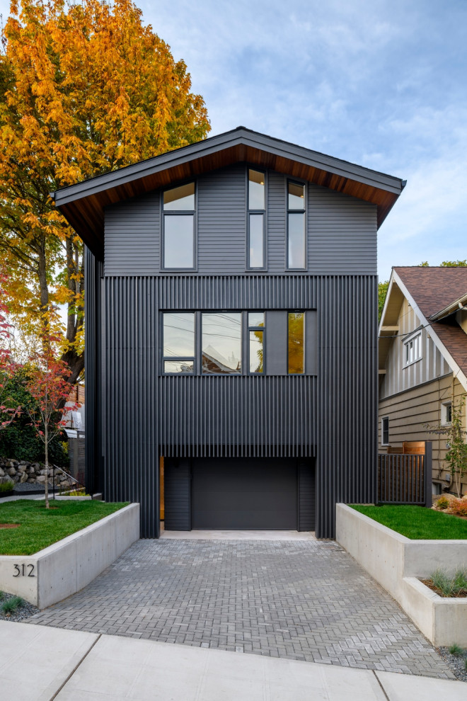 This is an example of a mid-sized contemporary three-storey black house exterior in Seattle with mixed siding, a gable roof, a shingle roof and a grey roof.