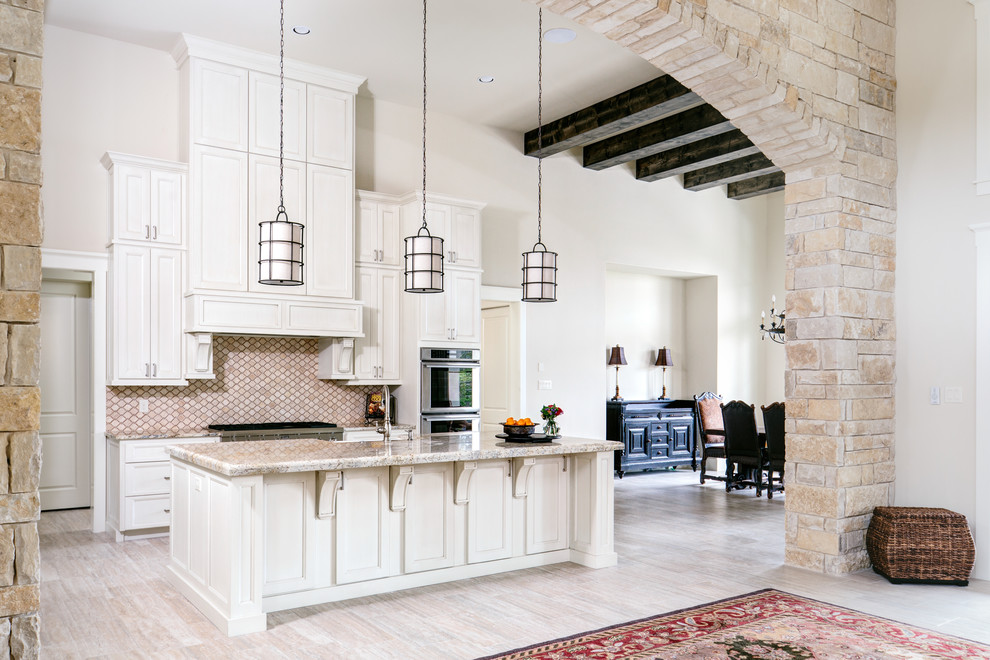 Photo of a mediterranean open plan kitchen in Austin with recessed-panel cabinets, beige cabinets, beige splashback, stainless steel appliances and with island.