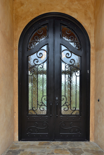 Photo of a large mediterranean front door in Austin with brown walls, travertine floors, a double front door and a brown front door.