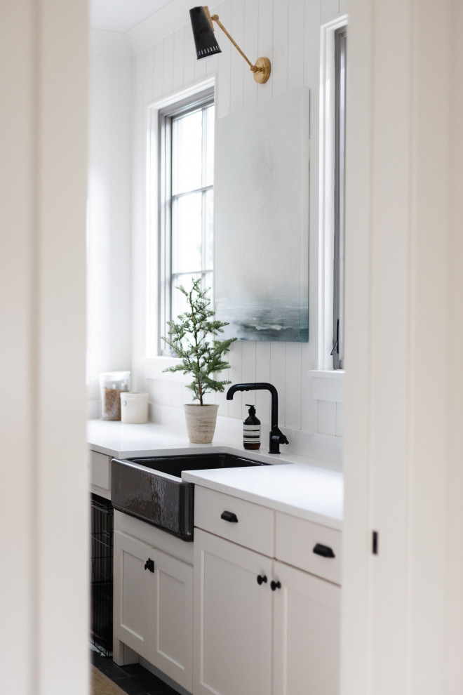 Exempel på en mellanstor klassisk vita vitt tvättstuga enbart för tvätt, med en rustik diskho, vita skåp, vita väggar, skiffergolv och en tvättmaskin och torktumlare bredvid varandra