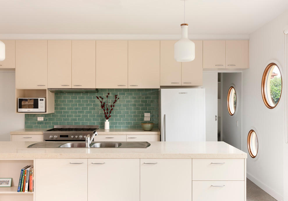 Mid-sized contemporary galley kitchen in Melbourne with a double-bowl sink, flat-panel cabinets, beige cabinets, green splashback, subway tile splashback, with island, quartz benchtops, stainless steel appliances and beige benchtop.