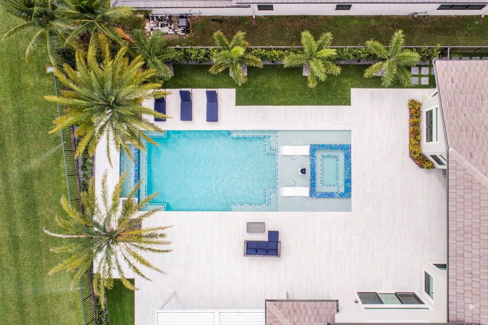 Inspiration for a large modern backyard rectangular infinity pool in Miami with a hot tub.