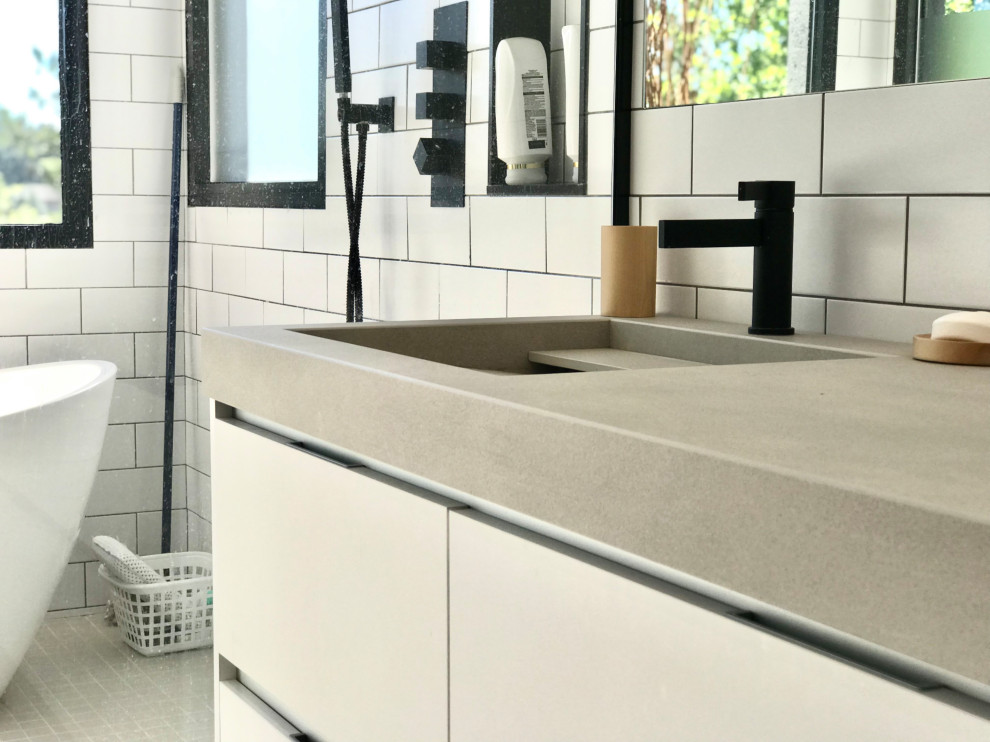 Idéer för att renovera ett mellanstort funkis grå grått en-suite badrum, med släta luckor, vita skåp, ett fristående badkar, vit kakel, ett integrerad handfat, kaklad bänkskiva, med dusch som är öppen, en kantlös dusch, porslinskakel, klinkergolv i keramik och grått golv