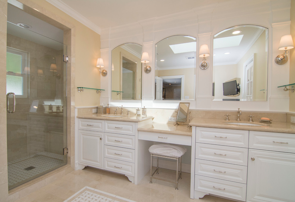 Inspiration for a mid-sized traditional master bathroom in Los Angeles with an undermount sink, raised-panel cabinets, white cabinets, marble benchtops, a corner shower, beige tile, yellow walls, marble floors, a freestanding tub, a one-piece toilet and stone tile.