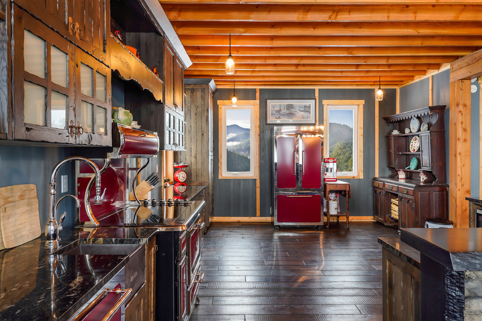Example of a large mountain style galley eat-in kitchen design with a farmhouse sink, recessed-panel cabinets, brown cabinets, quartzite countertops, colored appliances and an island