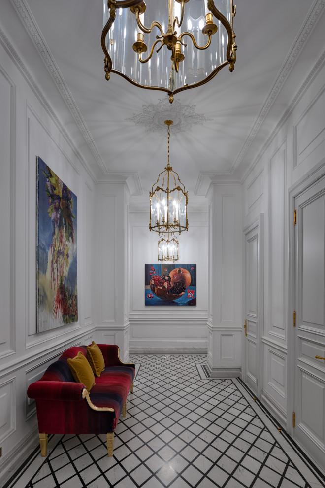 На фото: большой коридор: освещение в классическом стиле с белыми стенами, мраморным полом, белым полом, кессонным потолком и панелями на части стены