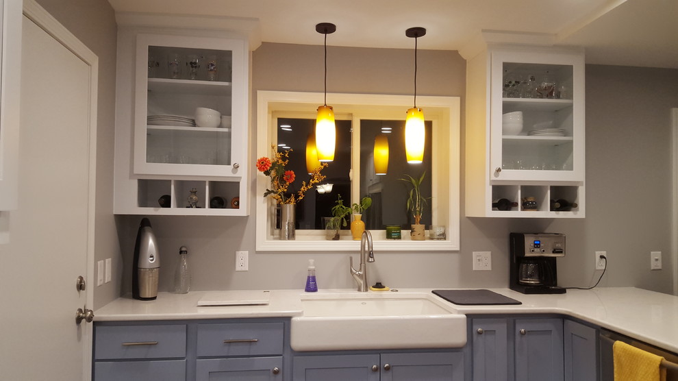 Example of a mid-sized transitional u-shaped vinyl floor enclosed kitchen design with a farmhouse sink, recessed-panel cabinets, blue cabinets, quartz countertops, stainless steel appliances and a peninsula