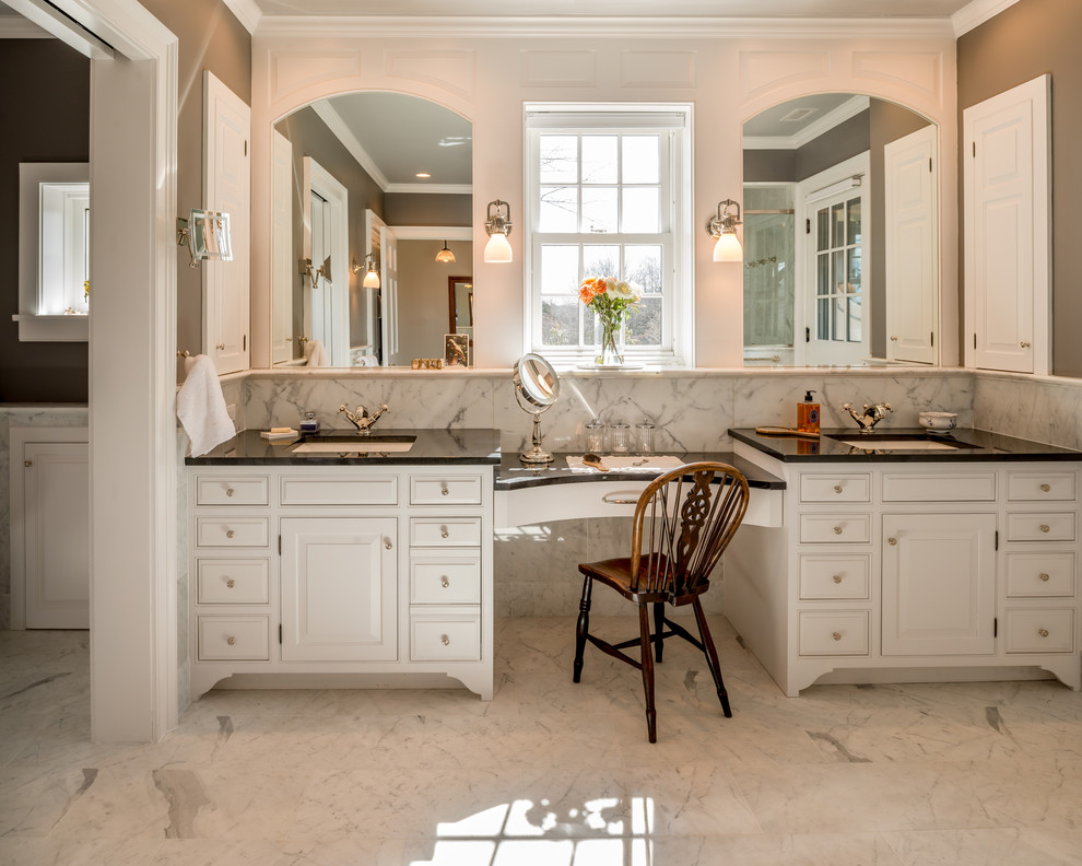 Photo of a large traditional master bathroom in Philadelphia with an undermount sink, raised-panel cabinets, white cabinets, white tile, stone tile, grey walls, marble floors, grey floor, a corner shower, a hinged shower door and black benchtops.