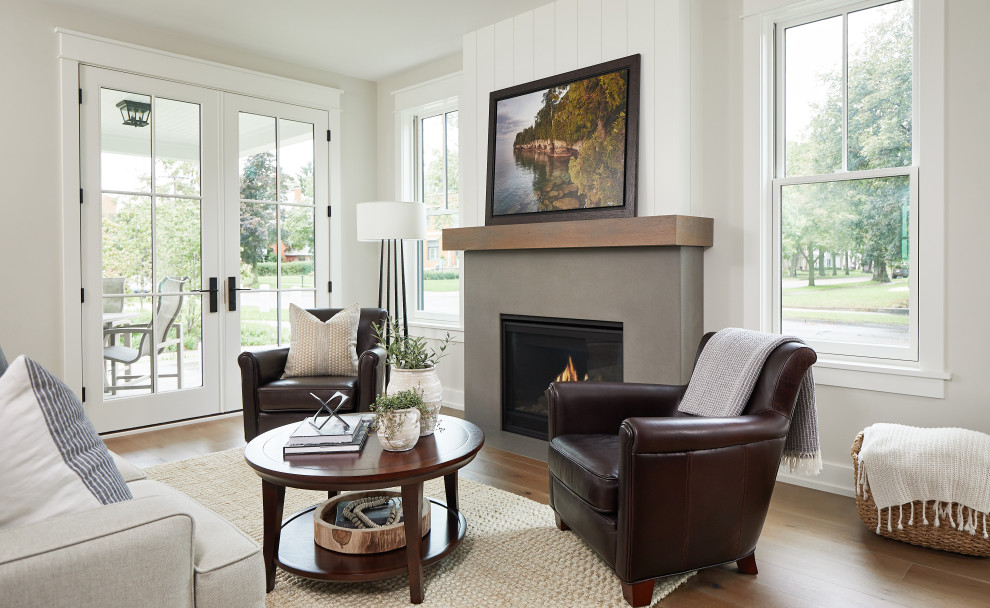 This is an example of a mid-sized country open concept living room in Grand Rapids with white walls, medium hardwood floors, a standard fireplace and a concrete fireplace surround.