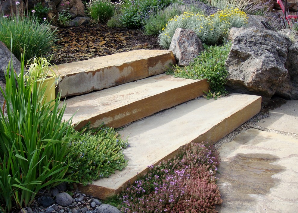 This is an example of a mediterranean backyard partial sun xeriscape in Other with natural stone pavers.
