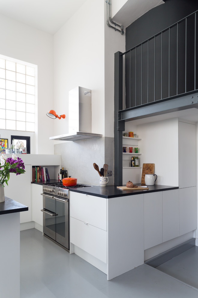 Photo of a large eclectic u-shaped eat-in kitchen in London with an undermount sink, flat-panel cabinets, white cabinets, solid surface benchtops, white splashback, cement tile splashback, stainless steel appliances and with island.