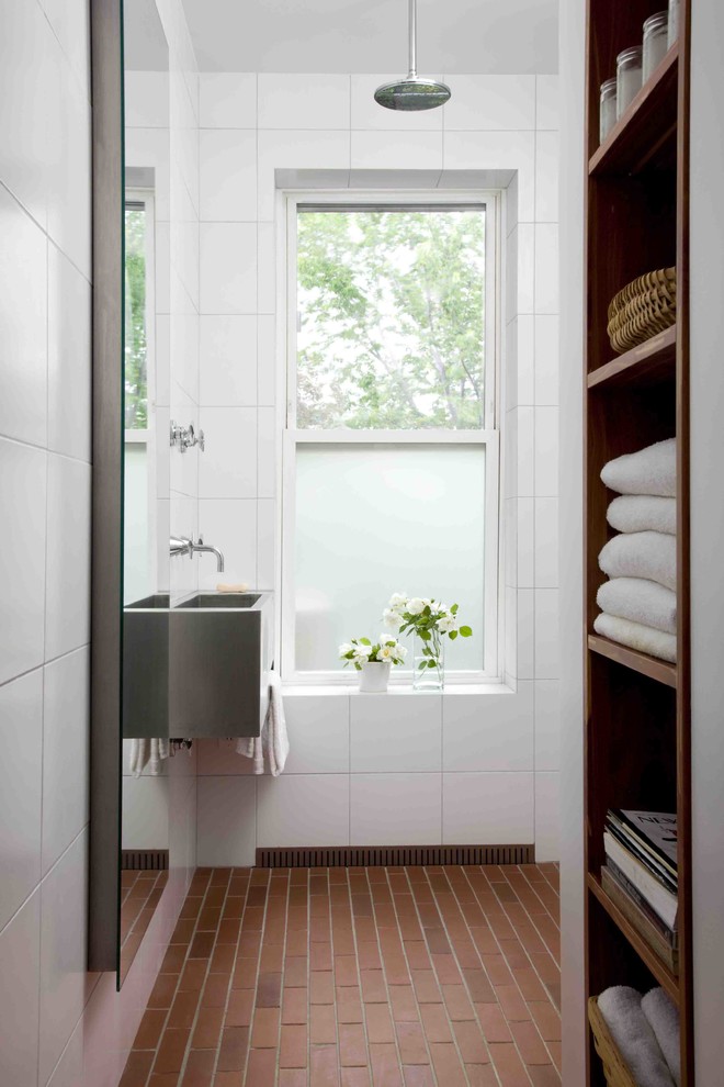 Design ideas for a small contemporary bathroom in New York with a wall-mount sink, white walls, open cabinets, stainless steel benchtops, white tile, porcelain tile, brick floors, a curbless shower and dark wood cabinets.