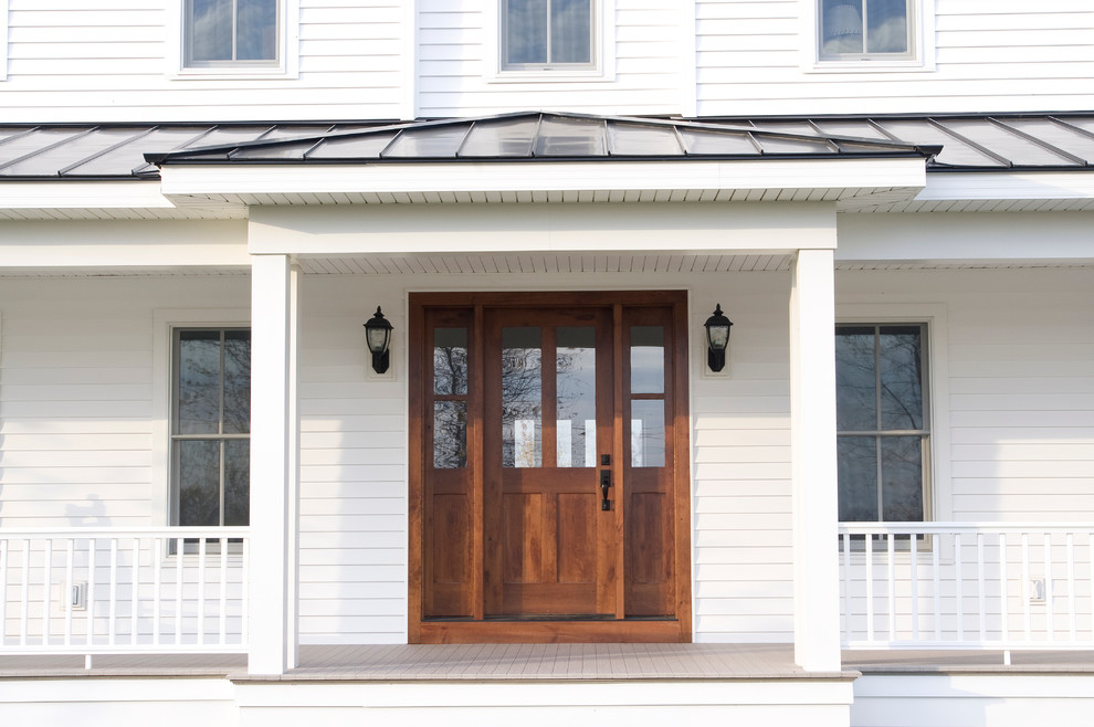This is an example of a large country front door in Other with white walls, a single front door and a dark wood front door.