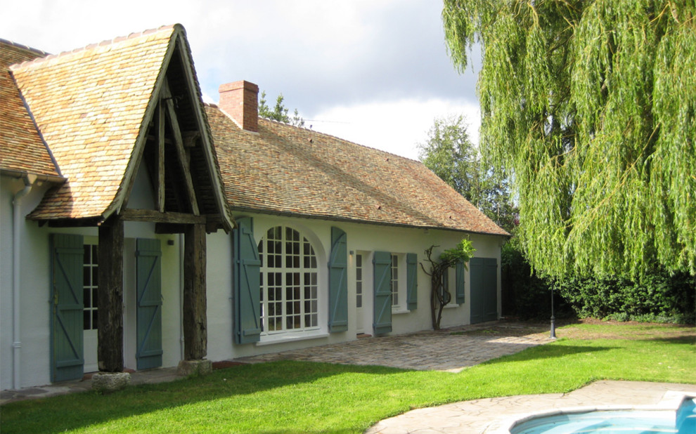 This is an example of a contemporary two-storey adobe white house exterior in Other with a gable roof and a tile roof.