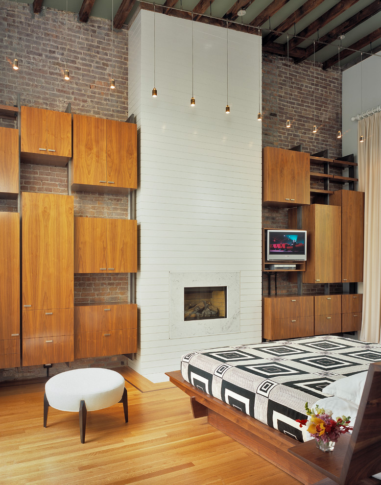 Photo of a contemporary bedroom in New York with a standard fireplace and a brick fireplace surround.