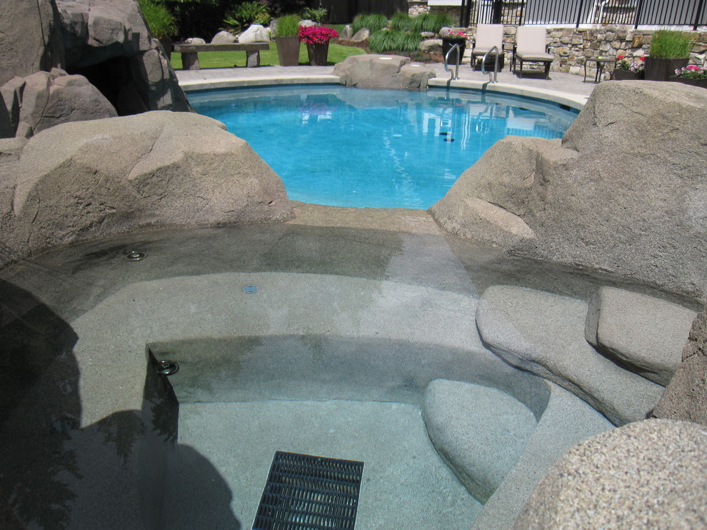 Design ideas for a mid-sized arts and crafts backyard custom-shaped natural pool in Vancouver with a hot tub and concrete slab.