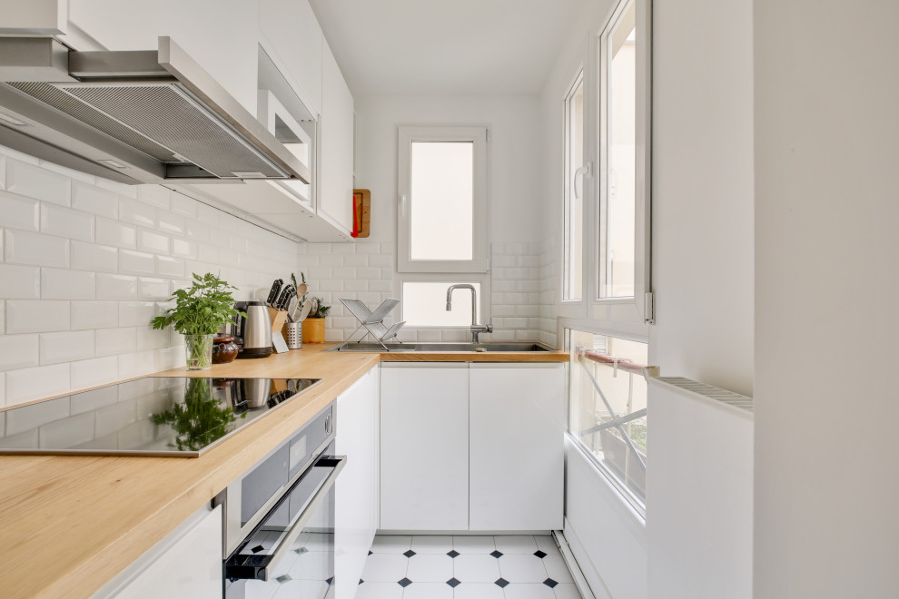 Inspiration for a small scandinavian l-shaped separate kitchen in Paris with a drop-in sink, flat-panel cabinets, white cabinets, wood benchtops, white splashback, subway tile splashback, stainless steel appliances, no island, white floor and beige benchtop.