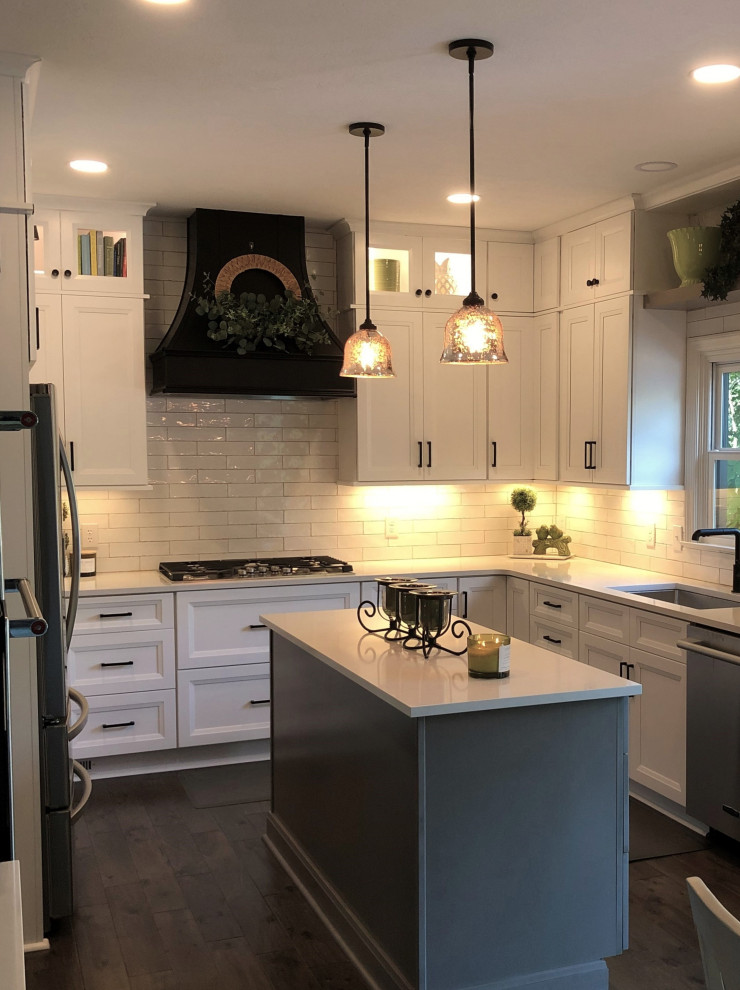 Mid-sized transitional dark wood floor and brown floor eat-in kitchen photo with an undermount sink, flat-panel cabinets, white cabinets, quartz countertops, white backsplash, porcelain backsplash, stainless steel appliances, an island and white countertops