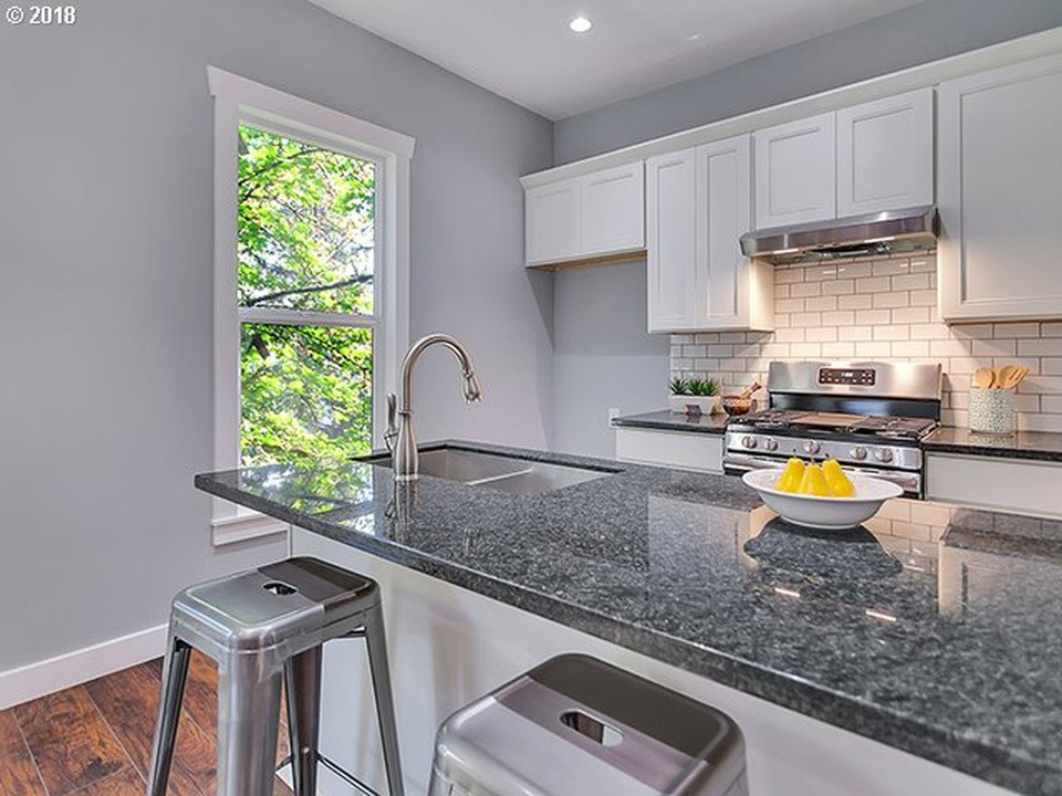 Small arts and crafts galley eat-in kitchen in Portland with a double-bowl sink, recessed-panel cabinets, white cabinets, granite benchtops, grey splashback, subway tile splashback, stainless steel appliances, medium hardwood floors, a peninsula, brown floor and grey benchtop.