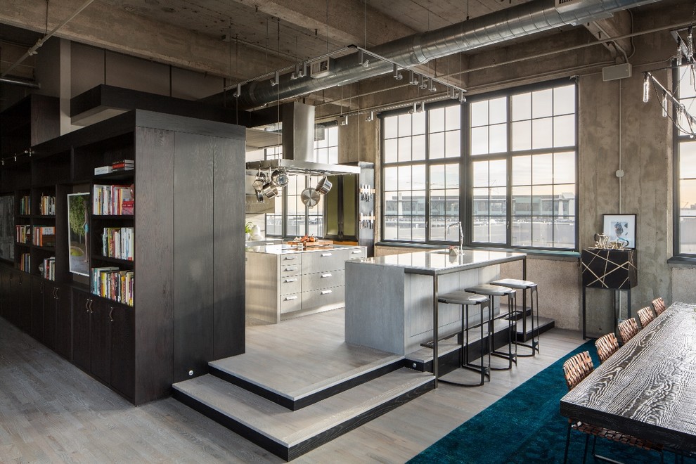 This is an example of a mid-sized industrial l-shaped open plan kitchen in Denver with flat-panel cabinets and multiple islands.