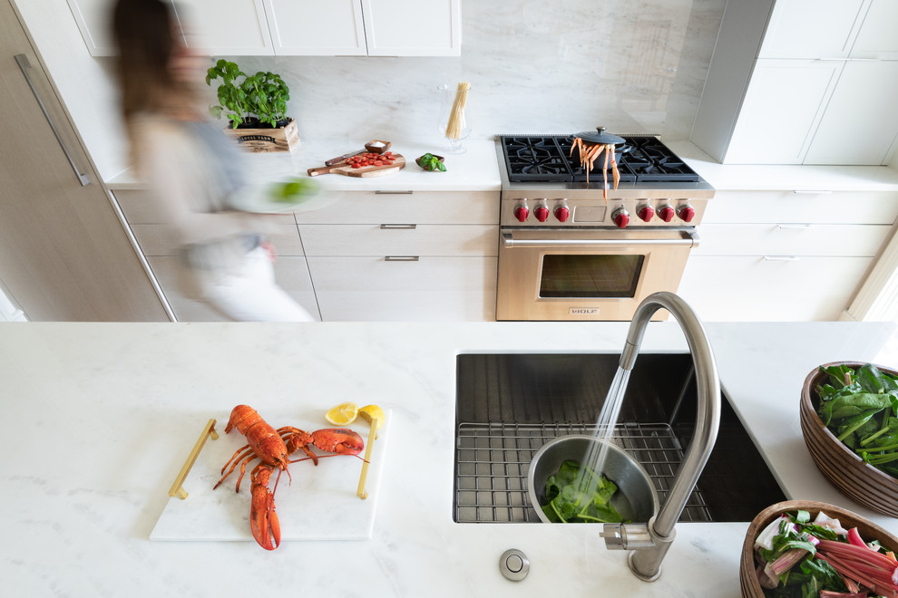This is an example of a mid-sized modern galley eat-in kitchen in DC Metro with a single-bowl sink, flat-panel cabinets, light wood cabinets, marble benchtops, grey splashback, marble splashback, stainless steel appliances, dark hardwood floors, with island, brown floor and white benchtop.
