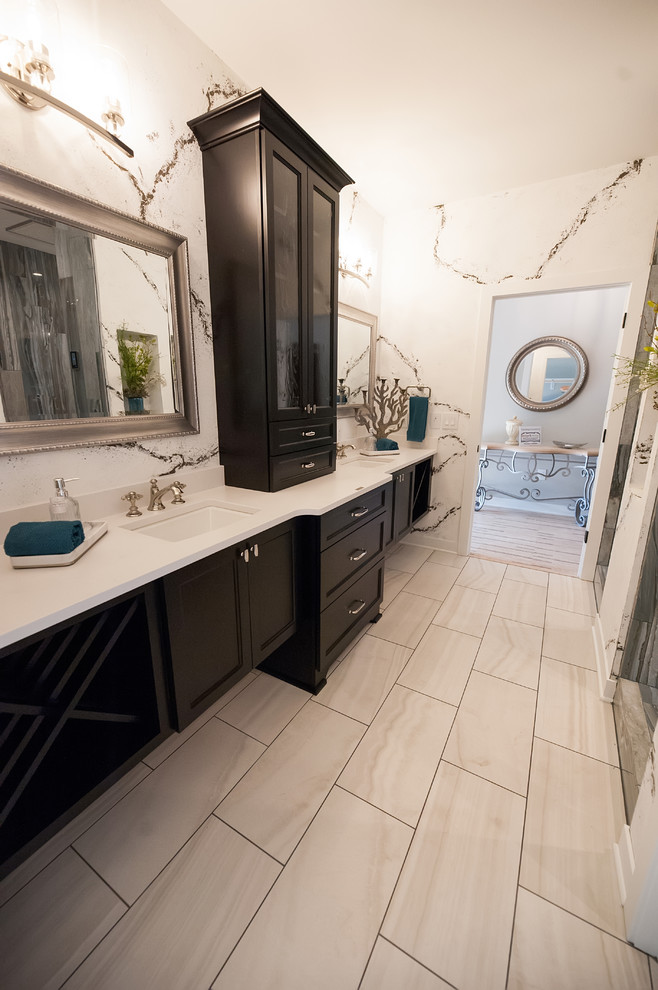 This is an example of an expansive contemporary master wet room bathroom in Milwaukee with glass-front cabinets, gray tile, ceramic tile, white walls, ceramic floors, white floor, an open shower, black cabinets, a one-piece toilet, an undermount sink and white benchtops.