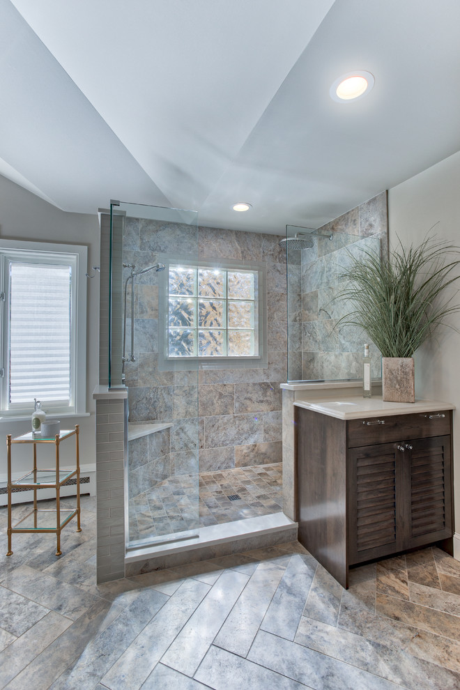 Design ideas for an expansive beach style master bathroom in Denver with louvered cabinets, medium wood cabinets, a freestanding tub, a corner shower, a two-piece toilet, multi-coloured tile, glass tile, beige walls, ceramic floors, an undermount sink and engineered quartz benchtops.