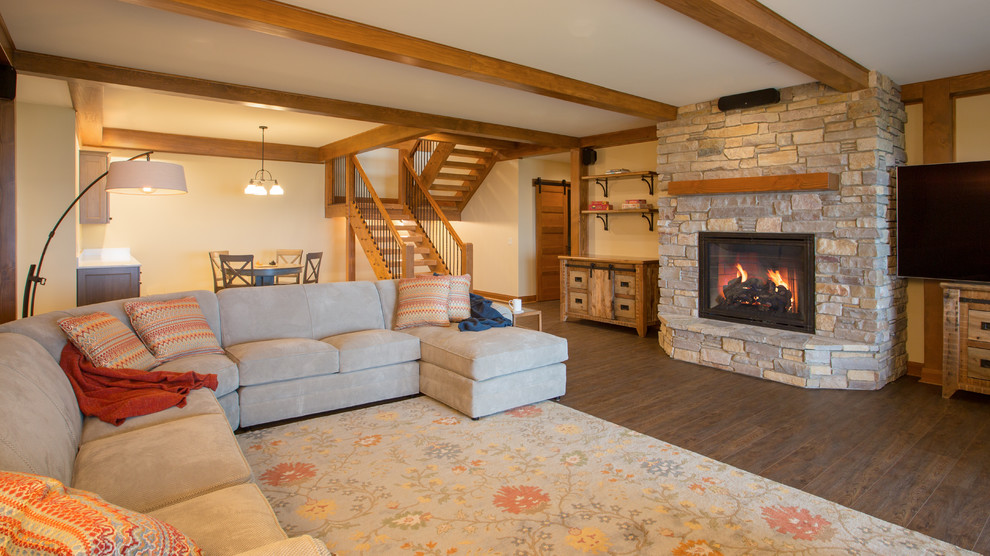 Large arts and crafts walk-out basement in Other with beige walls, a ribbon fireplace and a stone fireplace surround.