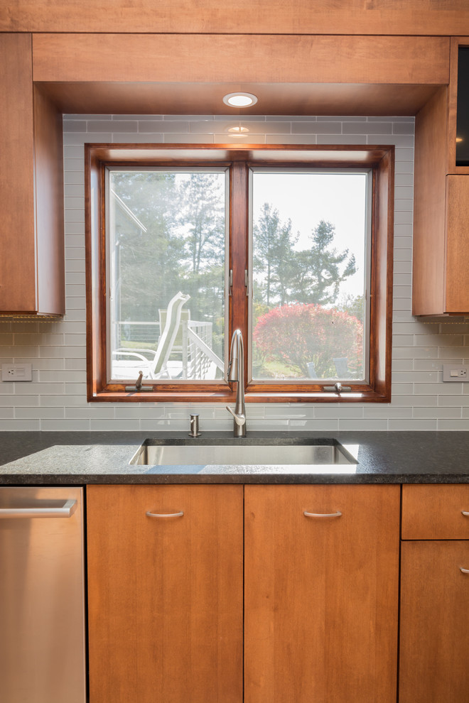 This is an example of a large transitional l-shaped open plan kitchen in Boston with an undermount sink, flat-panel cabinets, medium wood cabinets, granite benchtops, grey splashback, subway tile splashback, stainless steel appliances, light hardwood floors, with island and brown floor.