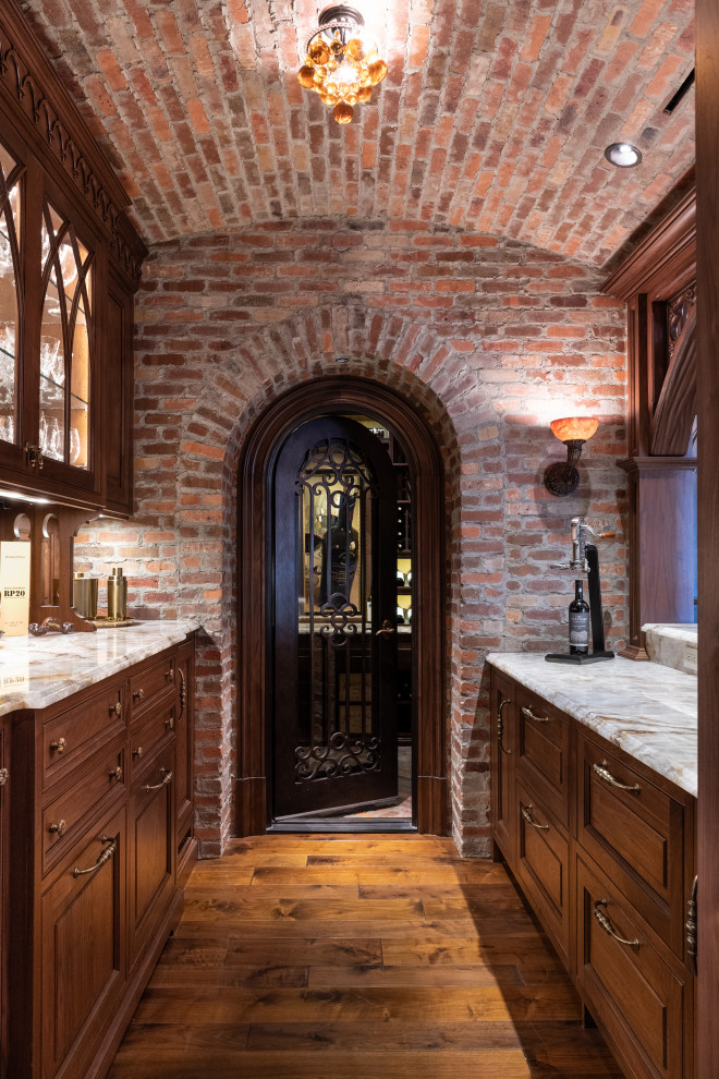 Mid-sized traditional galley home bar in Atlanta with raised-panel cabinets, medium wood cabinets, medium hardwood floors, brown floor and grey benchtop.