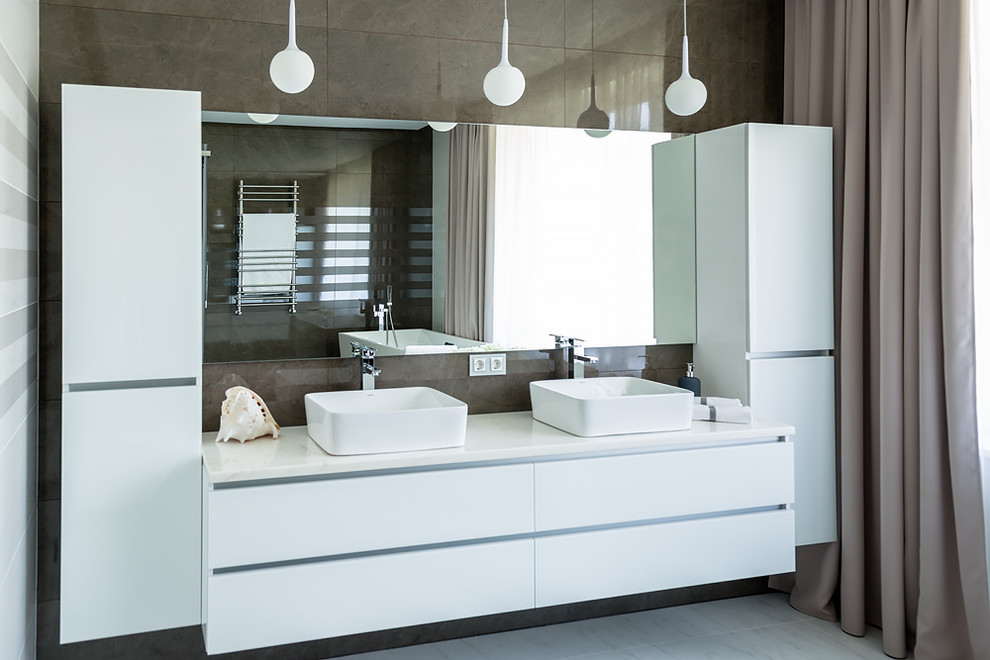 Photo of a mid-sized contemporary master bathroom in Novosibirsk with flat-panel cabinets, white cabinets, a freestanding tub, a corner shower, a wall-mount toilet, white tile, ceramic tile, white walls, porcelain floors, a drop-in sink, solid surface benchtops, white floor, a hinged shower door and white benchtops.