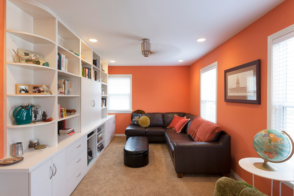 This is an example of a small transitional enclosed family room in Austin with orange walls, a concealed tv and carpet.